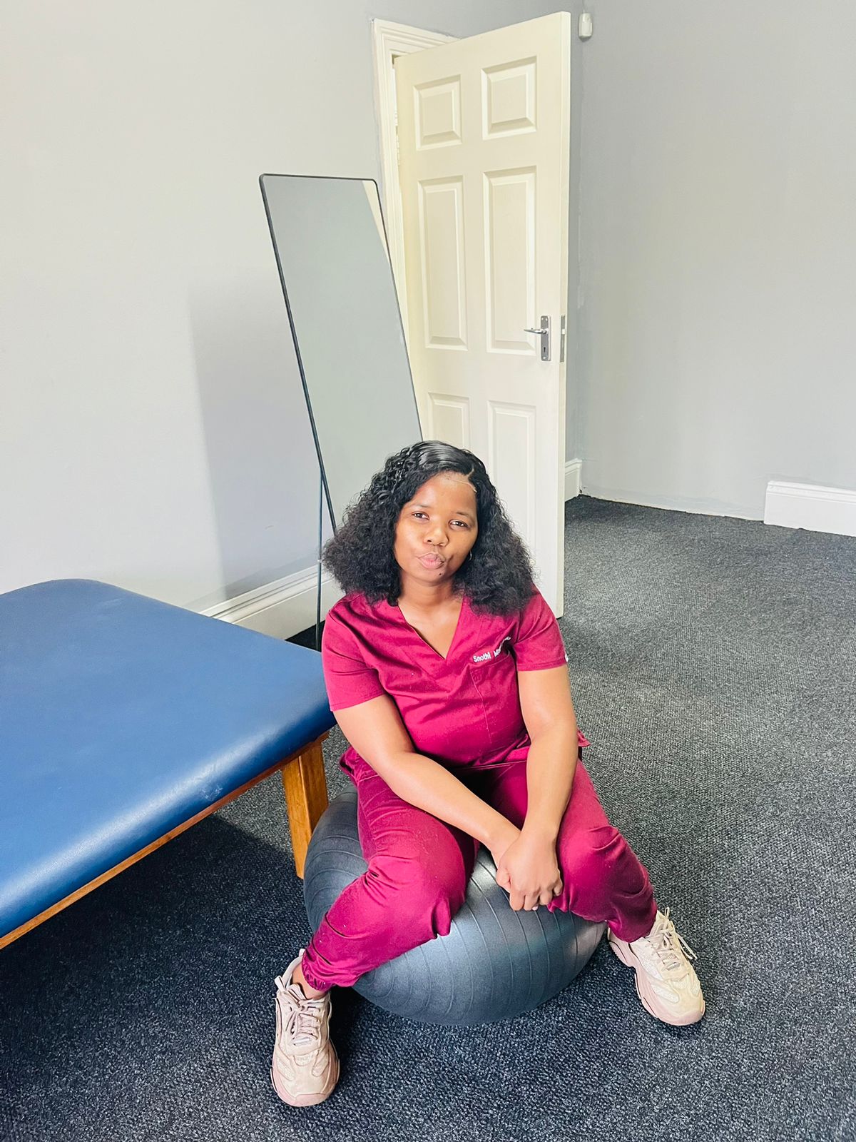Sthabile Mtshali seated on an exercise ball in her physiotherapy room